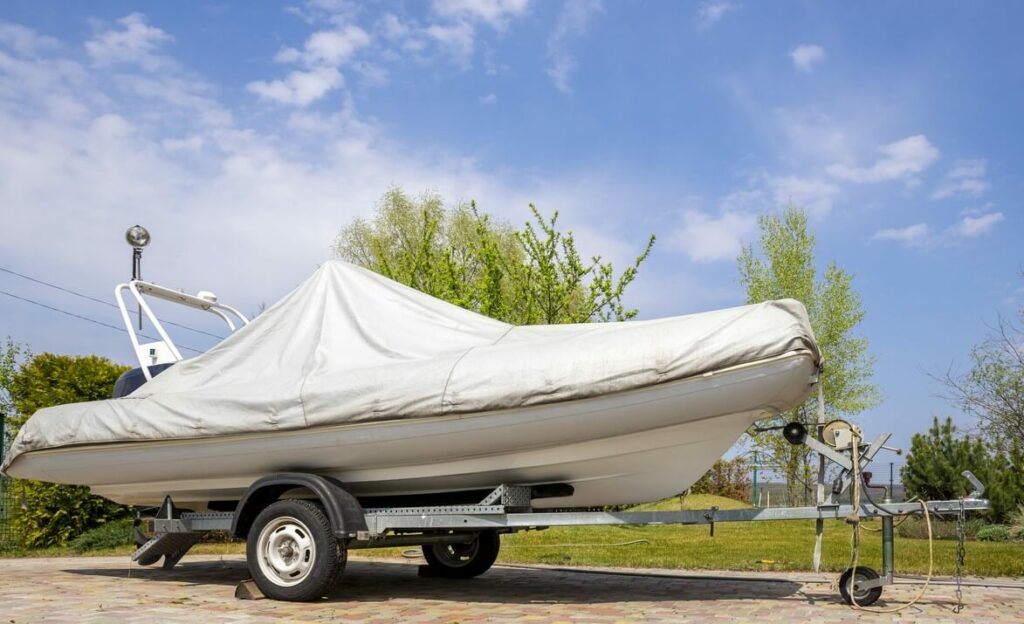 A boat sits covered on a trailer, ready for storage.