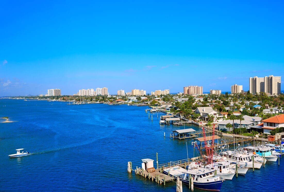 Boats docked in the ocean with a city in the background.