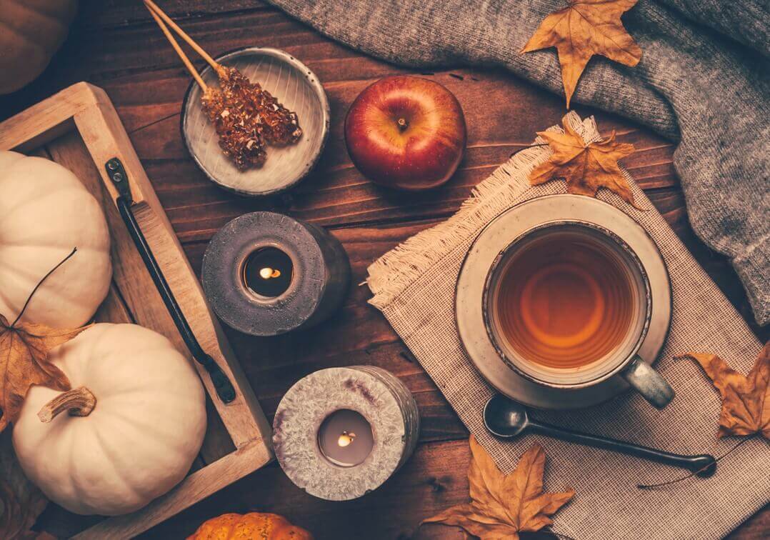 Fall decorations like candles, leaves, and pumpkins laid out on a wooden table.