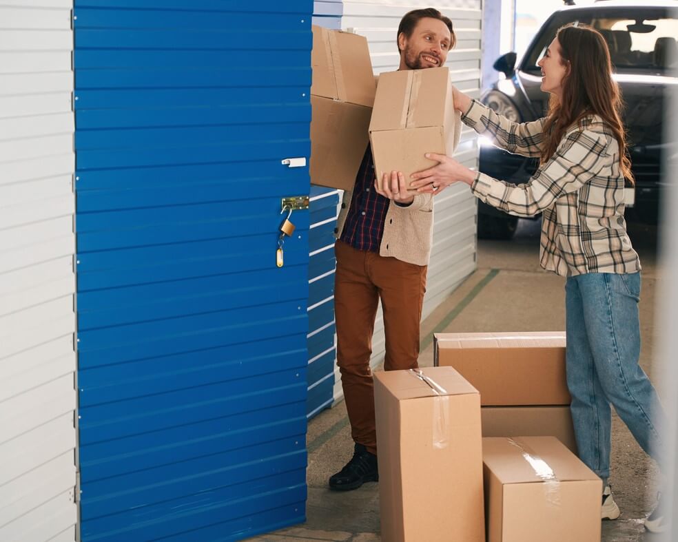 Couple moving boxes into a storage unit.