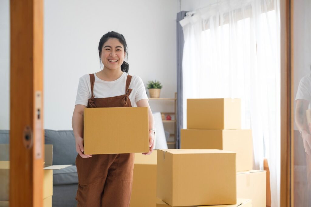 Woman moving storage boxes around as she settles into her new home.