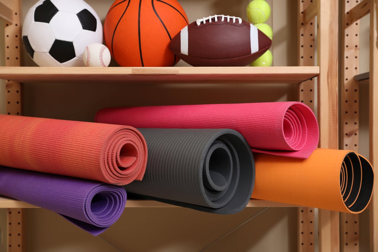 Exercise and sports equipment are shelved in a closet.