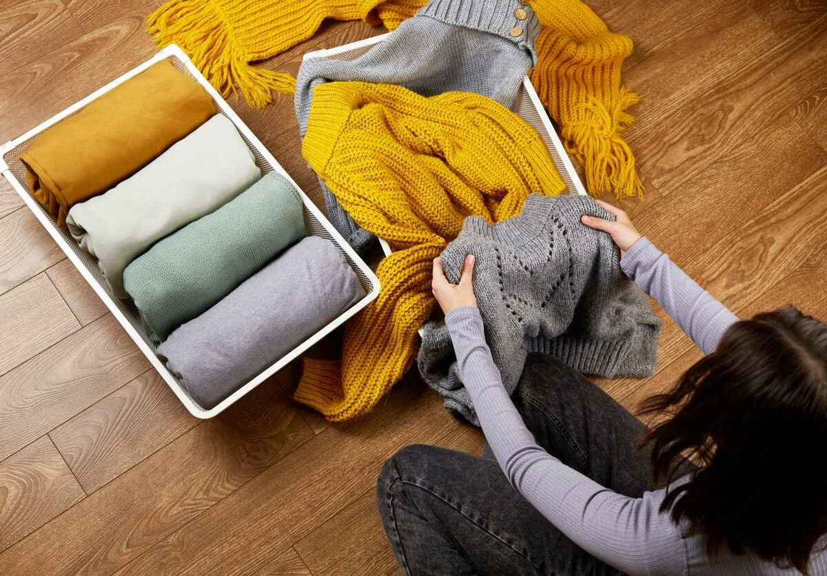 Young woman folding away clothes for the cold weather.