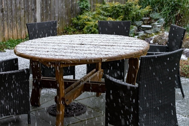 Outdoor furniture covered in snow, illustrating the risks of winter weather to unprotected belongings. 